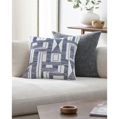 two blue and white pillows sitting on top of a couch next to a coffee table