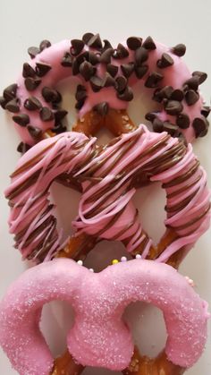 three doughnuts with pink frosting and chocolate sprinkles on them