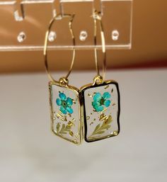 Clear resin with paper flower inside. Gold Flower Resin Earrings, Handmade Resin Flower Shaped Earrings, Handmade Resin Flower-shaped Earrings, Elegant Resin Flower-shaped Earrings, Elegant Resin Flower Earrings, Gold Resin Flower Charm Earrings, Gold Flower Charm Earrings In Resin, Resin Flower Charm Drop Earrings, Green Flower Hoop Earrings For Gift