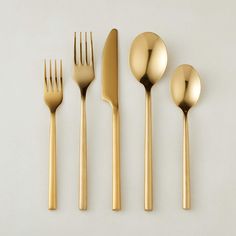 gold colored utensils are lined up on a white surface