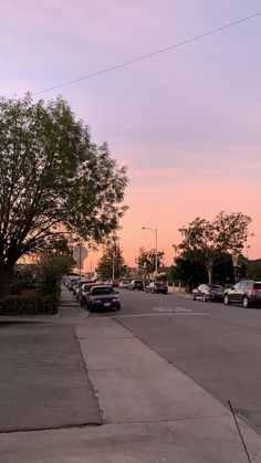 cars are parked on the side of the road at sunset or dawn in an urban area