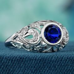 Add a delicate and unique aesthetic to your hand with this filigree ring crafted in elegant white gold, this exquisite ring showcases a breathtaking natural blue sapphire as its centerpiece. Intricate filigree detailing surrounding the sapphire enhances its allure, while multiple small diamonds adorn the ring, elevating its brilliance. With a design reminiscent of vintage elegance, this piece exudes timeless charm. Its beauty is truly captivating. CHARACTERISTICS Status: Made to order Origin: Th Elegant Sapphire Diamond Ring For Promise, Elegant Sapphire Diamond Promise Ring, Blue Sterling Silver Birthstone Ring With Diamond Accents, Elegant Royal Blue Gemstone Rings, Elegant Tanzanite Birthstone Ring For Promise, Elegant Sapphire Birthstone Ring For Promise, Elegant Sterling Silver Diamond Birthstone Ring, Elegant Sterling Silver Diamond Ring With Birthstone, Elegant Silver Diamond Ring With Birthstone