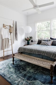 a bedroom with a bed, rug and ceiling fan in the corner next to a window