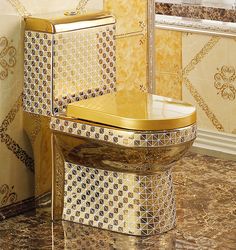 a gold toilet and sink in a bathroom with marble counter tops, patterned walls and flooring