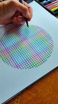 a person is drawing with colored pencils on paper