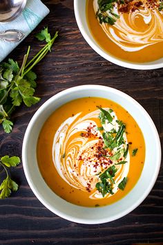 a white bowl filled with carrot soup and garnished with parsley on top