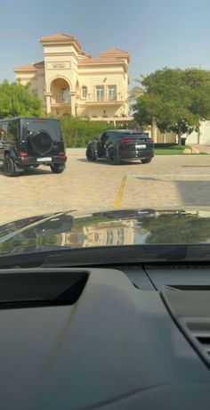 two cars parked in front of a large house