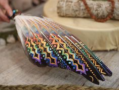 an artistically painted feather sitting on top of a wooden table