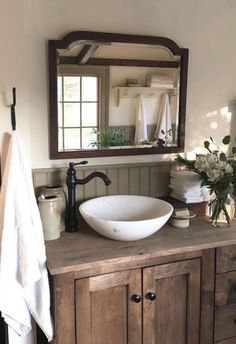 a bathroom sink sitting under a mirror next to a wooden counter top with towels hanging on it