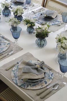 the table is set with blue and white dishes, silverware, and napkins