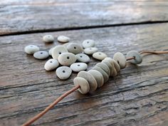 some white and grey buttons are on a wooden table with brown string attached to them