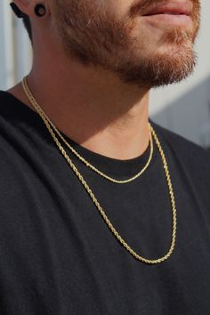 a close up of a man wearing a necklace and earring with a cell phone in his hand