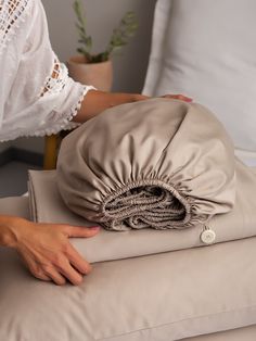 a woman laying on top of a bed covered in sheets and pillows with her hand resting on the pillow