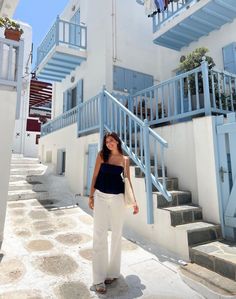 a woman standing in front of a blue and white building with steps leading up to it