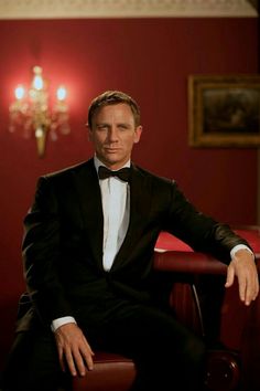 a man in a tuxedo sitting on a red chair