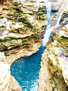 there is a waterfall in the middle of some rocks and blue water flowing down it