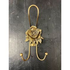 a gold flower shaped hook on a black wall