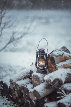 a lantern sitting on top of snow covered logs