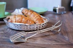 some croissants are in a pan on a table next to a cup and saucer