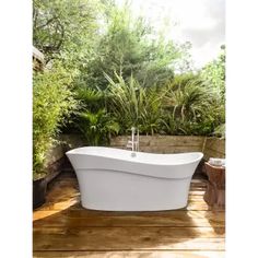 a white bath tub sitting on top of a wooden floor next to potted plants