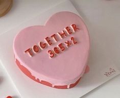 a pink heart shaped cake with the words together in red icing on white paper