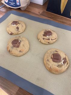 four chocolate chip cookies sitting on top of a cookie sheet next to a bag of peanut butter