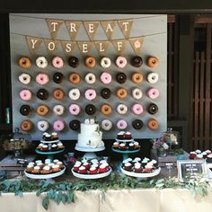 a table topped with donuts and cupcakes next to a sign that says treat yo self