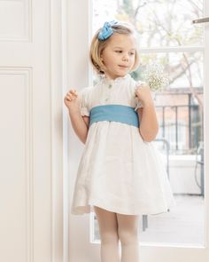 This beautiful party dress is handcrafted by our expert hands in Spain. Made off white linen with delicate mother-of-pearl buttons on the front, puff sleeves and frilled collar, our Grace style is here to stay! Elegant blue linen sash for a sweet girly touch to finished off by a spectacular big bow around the back. Dress like a princess in this beautiful bespoke gown! Please allow 4 weeks between order and delivery for this bespoke piece Dress Like A Princess, Frilled Collar, Beautiful Party Dresses, Hand Smocked Dress, Dresses And Tights, Baby Boy Shirts, Girls Special Occasion Dresses, Milly Dress, Linen White