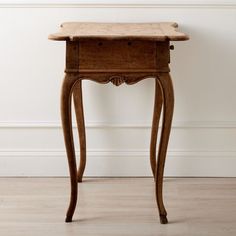 an old wooden table with drawers on it's sides, against a white wall