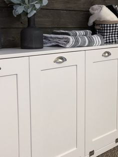 a white cabinet with two vases on top of it next to some folded towels