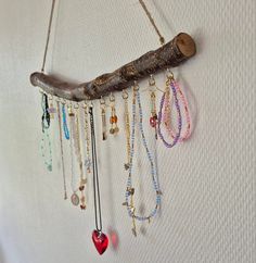 a wooden stick with many necklaces hanging from it's side on a wall