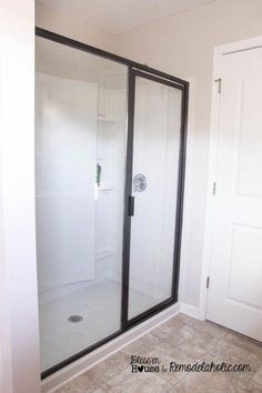 a bathroom with a walk in shower next to a white door and tile flooring