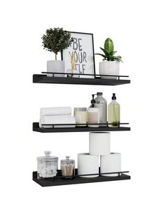 two black shelves with white towels, toiletries and plants