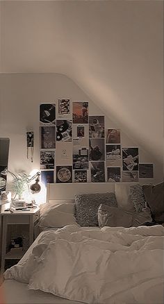 a bed with white sheets and pictures on the wall above it, along with a computer