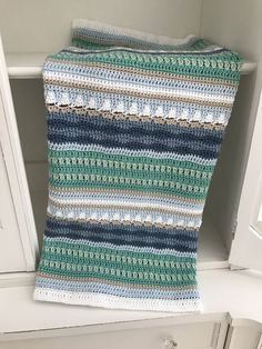 a crocheted blanket sitting on top of a white cabinet