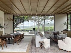 a living room filled with furniture next to a large glass wall window covered in trees