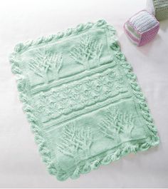 two crocheted items are laying on a white bed sheet next to each other