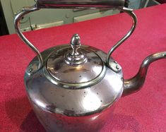 a silver tea kettle sitting on top of a red table