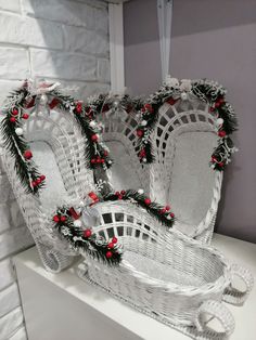 two white wicker baskets decorated with red berries and pine cones on top of a shelf