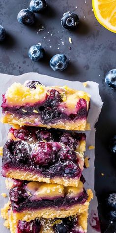 blueberry cheesecake bars stacked on top of each other with lemon wedges next to them