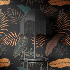 a lamp on a table in front of a wallpapered with leaves and plants