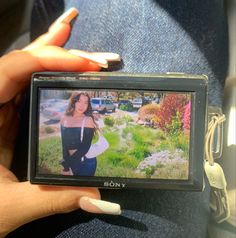 a woman holding up a camera to take a picture with her cell phone in hand