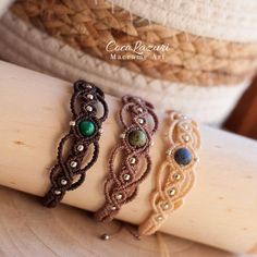 three different bracelets are sitting on a piece of wood with beads and stones in them