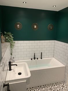 a bath tub sitting next to a white sink in a room with green walls and flooring