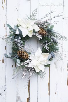 a wreath with white flowers and pine cones