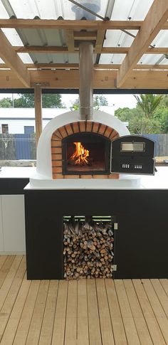 an outdoor pizza oven with wood burning in it's center and logs on the outside