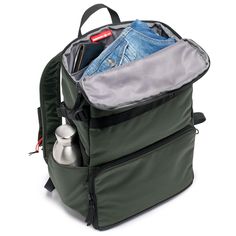 an open backpack filled with items on top of a white surface and zippered closures