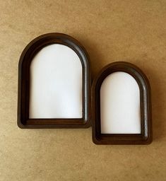 two oval wooden frames with white paper in them on a brown surface, one is open and the other is closed