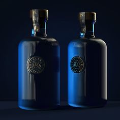 two blue bottles with gold emblems sitting side by side on a dark background, one is empty