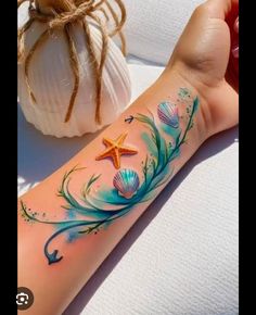 a person with a tattoo on their arm next to a seashell and starfish